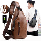 Brown leather sling bag with USB charging port and earbuds, displayed with a person wearing a black bag.
