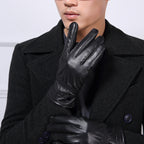 Person wearing black leather gloves with a dark coat against a light background