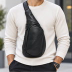 A man wearing a black leather crossbody sling bag with a wide adjustable strap, styled over a cream ribbed knit sweater and black trousers.