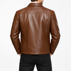 Brown - A man viewed from the back wearing a brown leather jacket and black jeans against a plain white studio background.