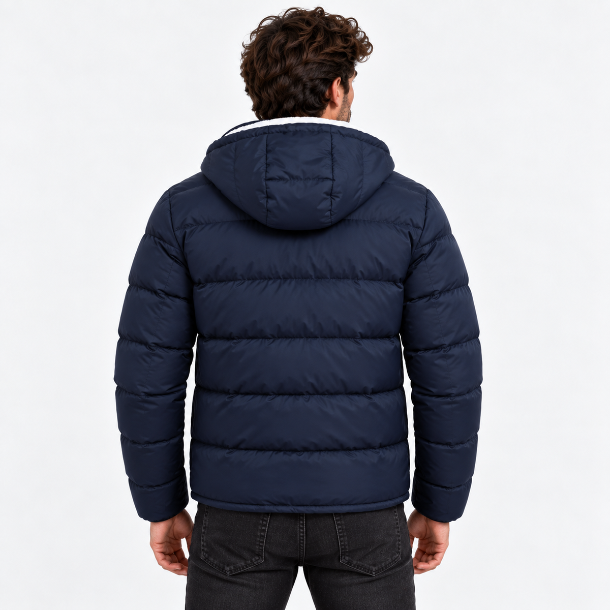 Navy Blue - A man viewed from behind wearing a navy blue hooded puffer jacket, paired with dark gray jeans, against a plain white studio background.
