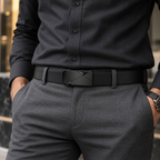 A close-up of a man wearing a black leather belt with a geometric metal buckle, paired with a dark charcoal dress shirt and gray trousers.