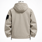 Earth Brown - A light beige hooded jacket shown from the back on a mannequin, featuring a black rectangular patch on the left sleeve and elastic cuffs.