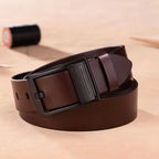Brown leather belt with a black buckle on a beige surface