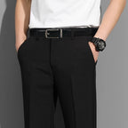 Person wearing black pants with a white shirt and black belt on a gray background