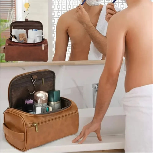 Brown toiletry bag with travel items next to a person shaving in front of a mirror.