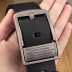 Black belt with silver buckle held in a hand, featuring engraved text.