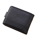 A black textured leather bifold wallet with decorative stitching, displayed on a light wood surface next to a white smartphone, with neutral-colored boxes in the background.