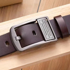 Brown leather belt with a silver buckle on a wooden surface