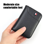 Black slim vegan leather card holder held in one hand to show its compact size.