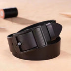 Black leather belt with a silver buckle on a beige background