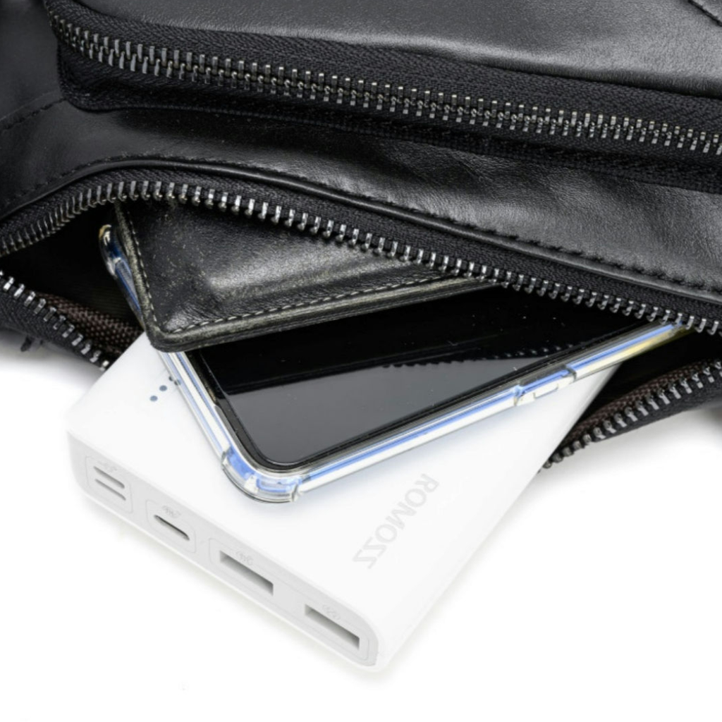 A close-up of a black leather zippered pouch with its zipper open, showing a white portable power bank and a smartphone tucked inside.