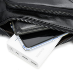 A close-up of a black leather zippered pouch with its zipper open, showing a white portable power bank and a smartphone tucked inside.