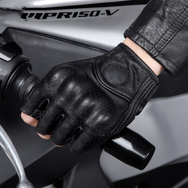 Black motorcycle glove on a gloved hand gripping a handlebar with a motorcycle in the background.
