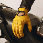 Yellow leather glove on a motorcycle seat with a helmet in the background