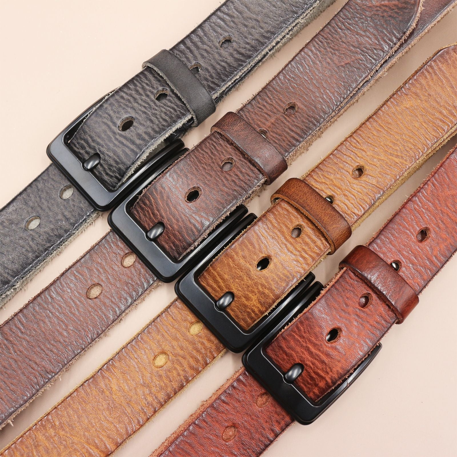 Set of leather belts with black buckles on a beige background