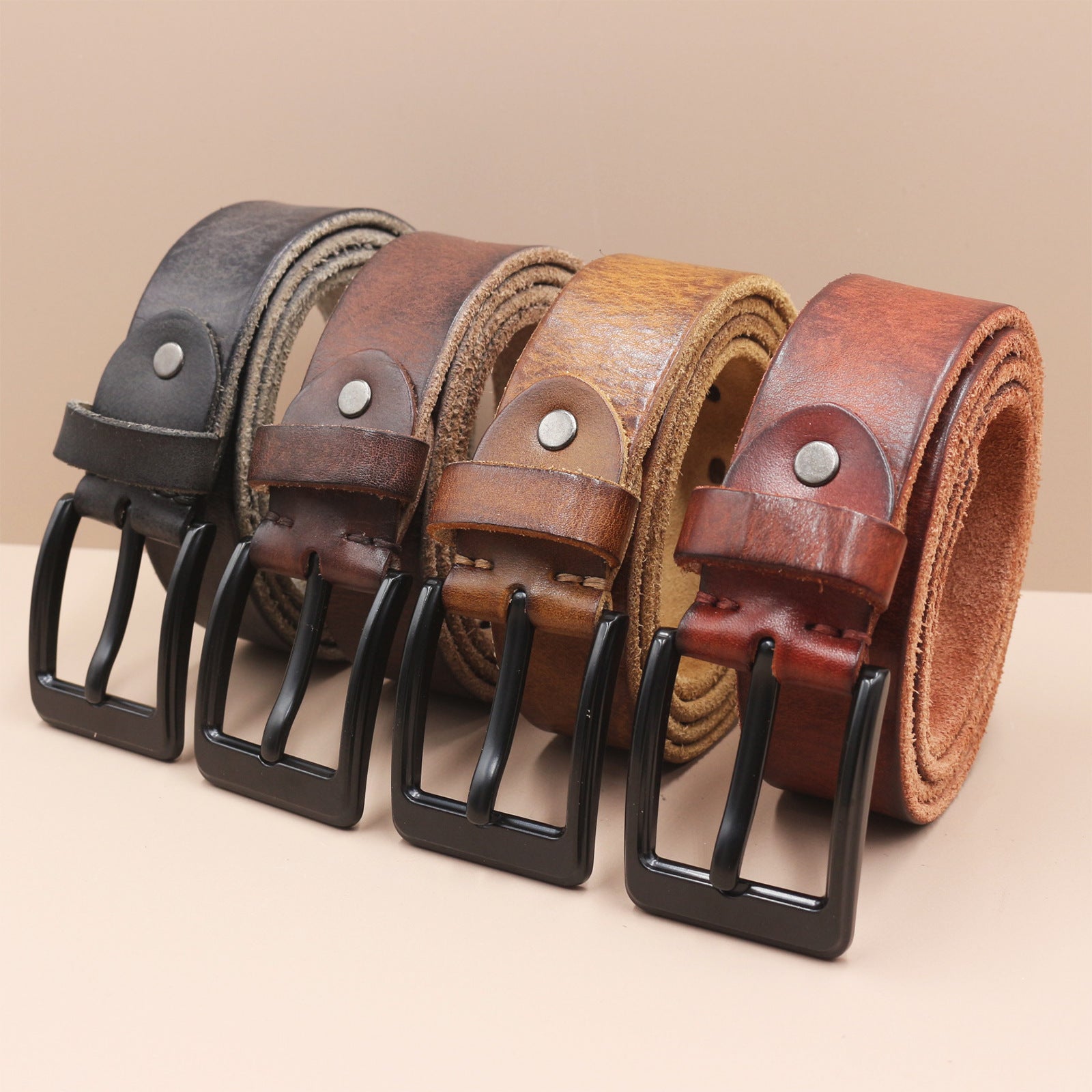 Set of leather belts with black buckles on a beige background