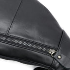 Close-up of a black faux leather bag with a silver zipper and metal hardware, set against a plain white background.