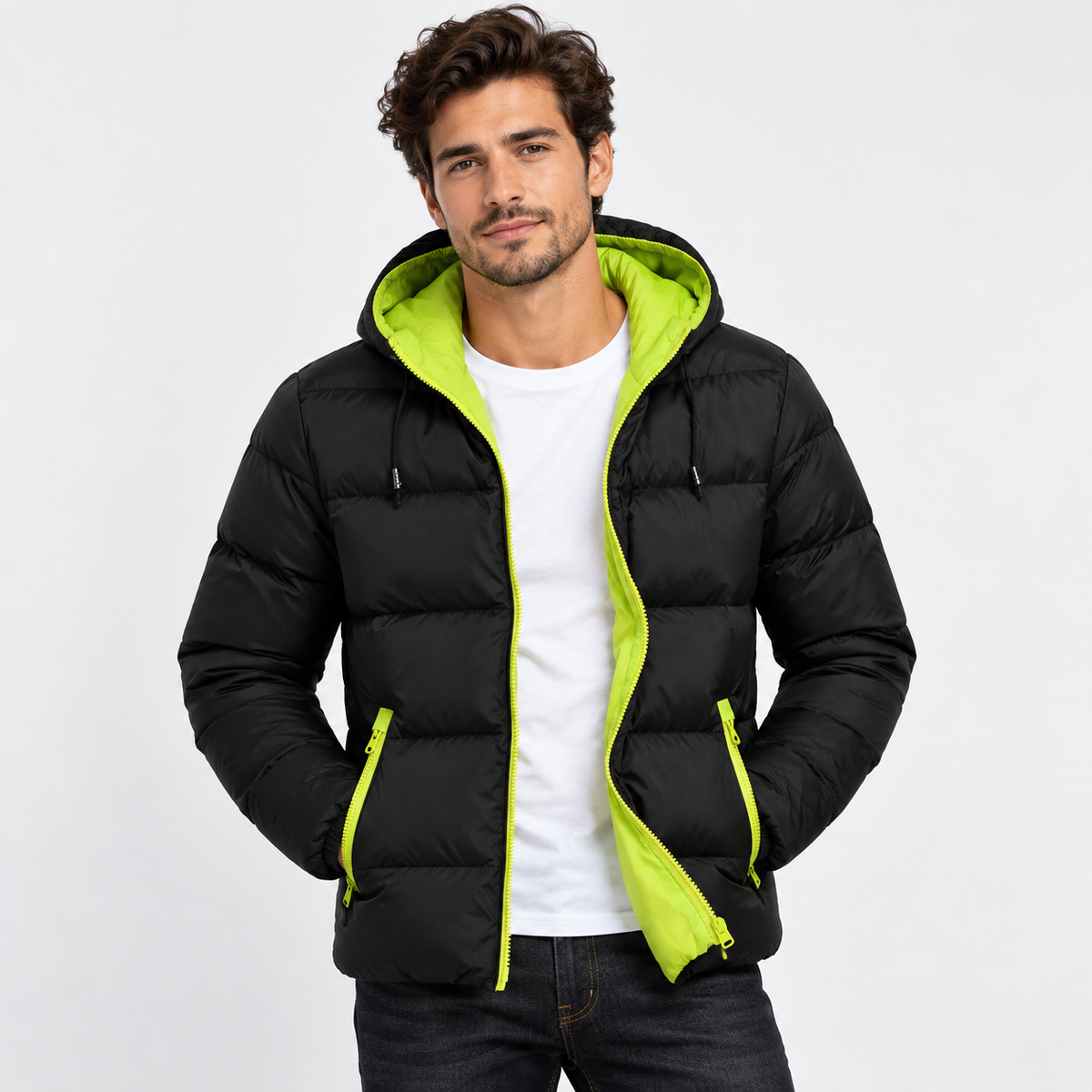Green - A man wearing a black hooded puffer jacket with a bright lime green interior lining and matching zipper accents, layered over a white t-shirt and dark jeans, against a plain light gray background.